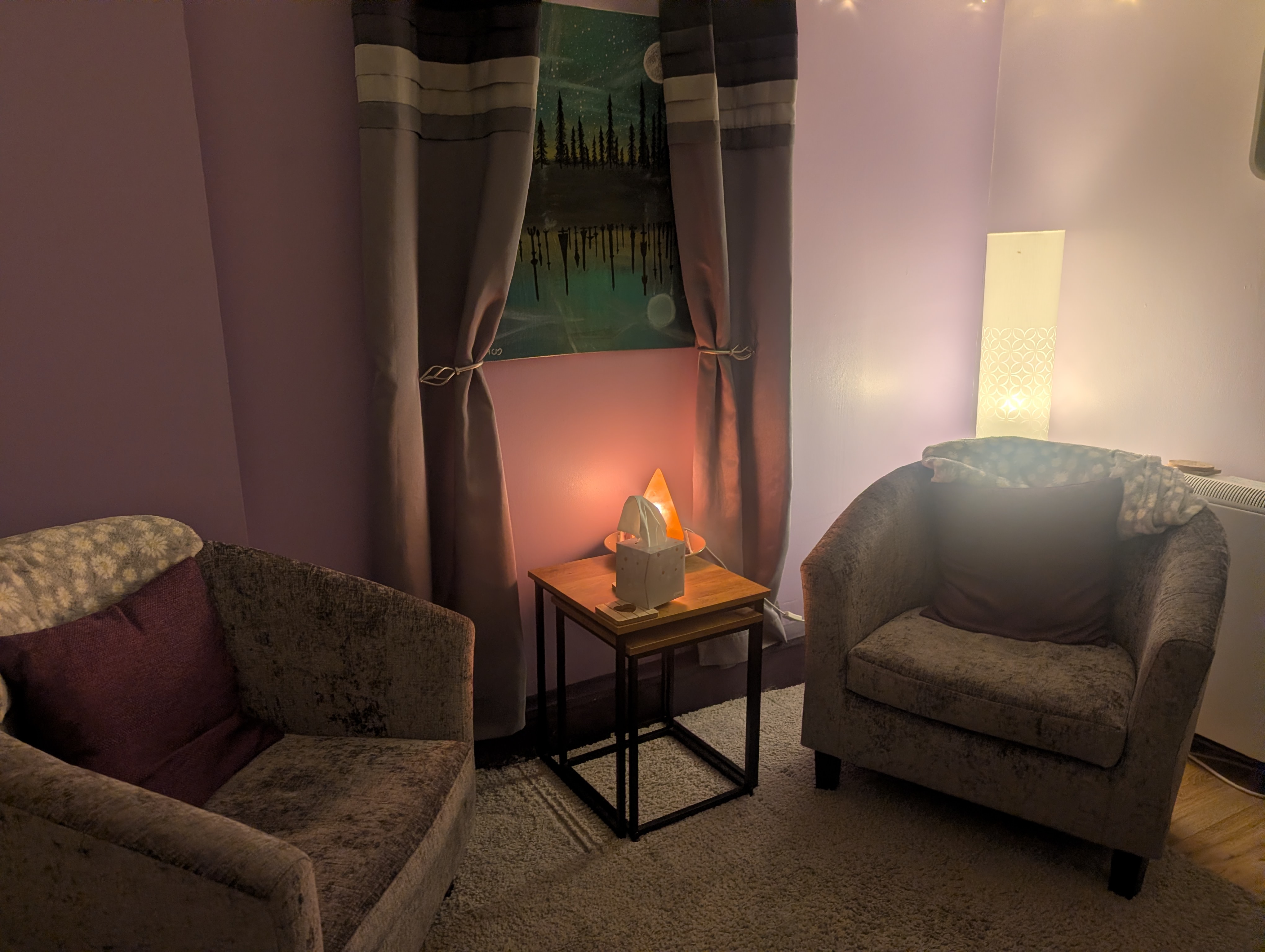 A calm, softly lit counselling room with two armchairs, a Himalayan salt lamp and a tasselled curtain.